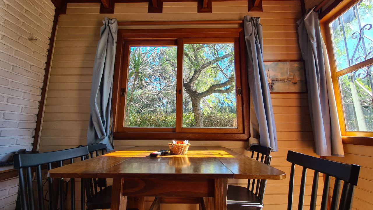 Comedor de una cabaña con vista al jardín por la ventana